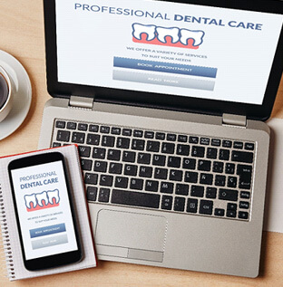 dental forms on laptop and phone on desk with supplies