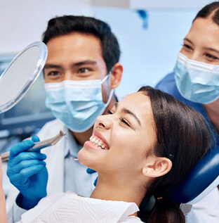 patiet smiling at reflection with dentist and assistant