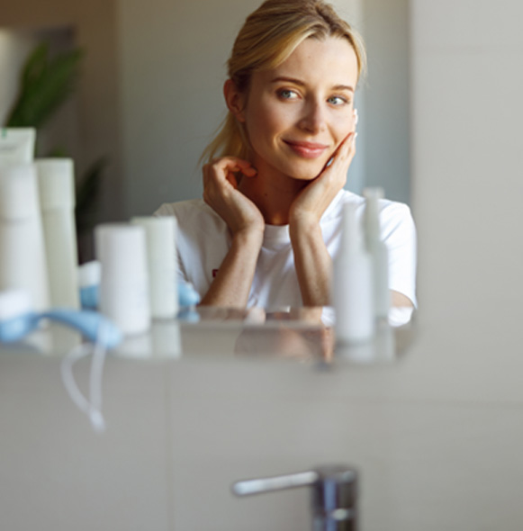 Woman looking at herself in bathroom mirror