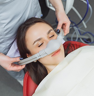 Dental assistant placing nasal mask on patient in treatment chair