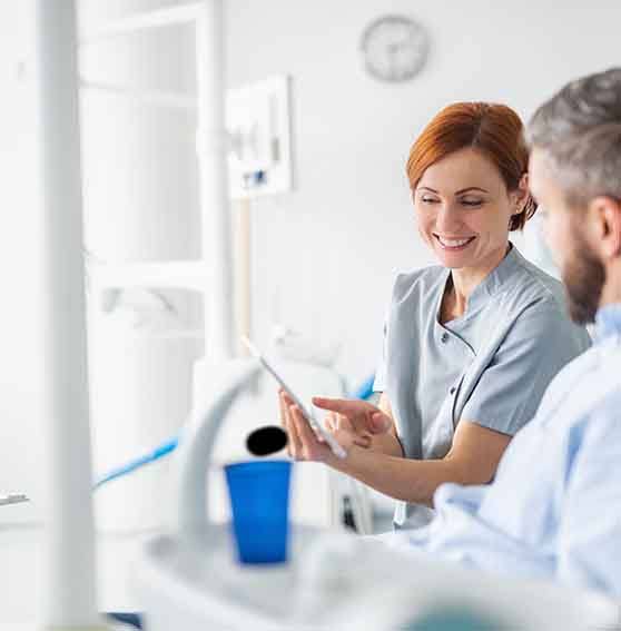 Smiling dentist showing patient image on tablet