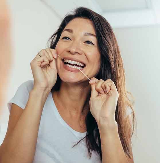 Woman smiling while flossing her teeth